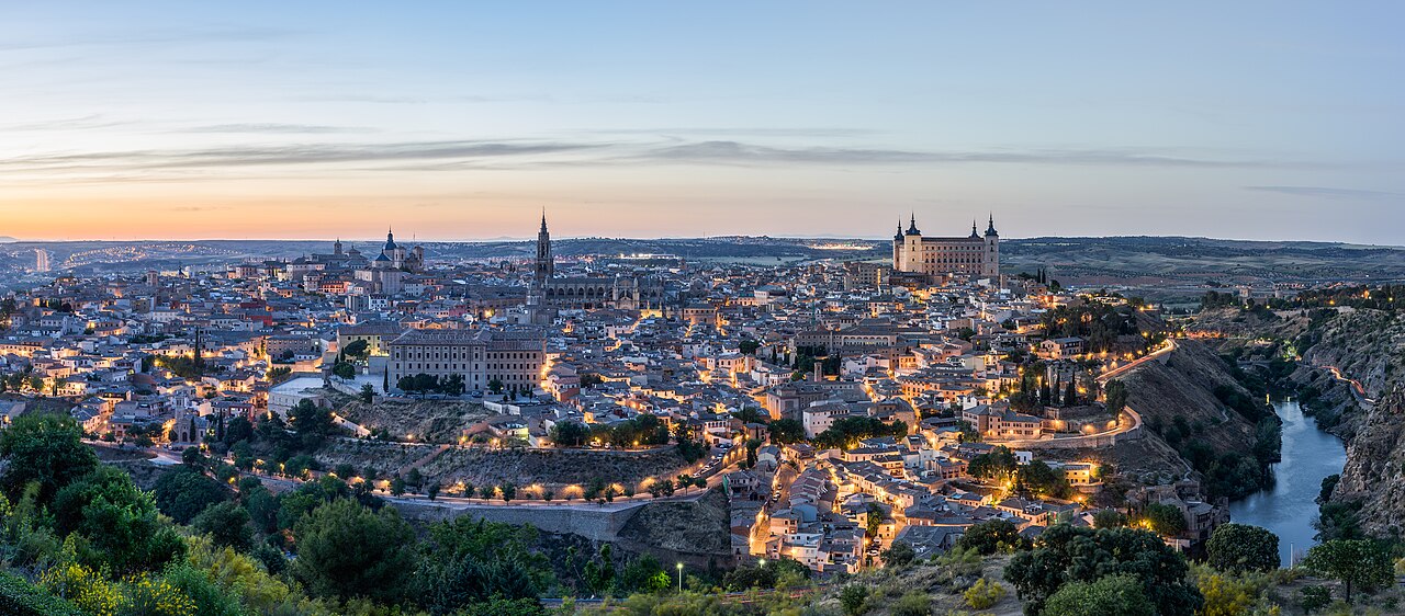 Vista panorámica de la ciudad de Toledo al atardecer con sus edificios históricos iluminados.