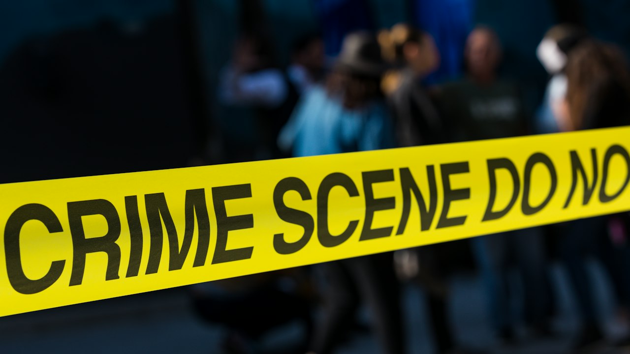 Cinta amarilla de precaución que delimita una escena de crimen en una calle urbana.