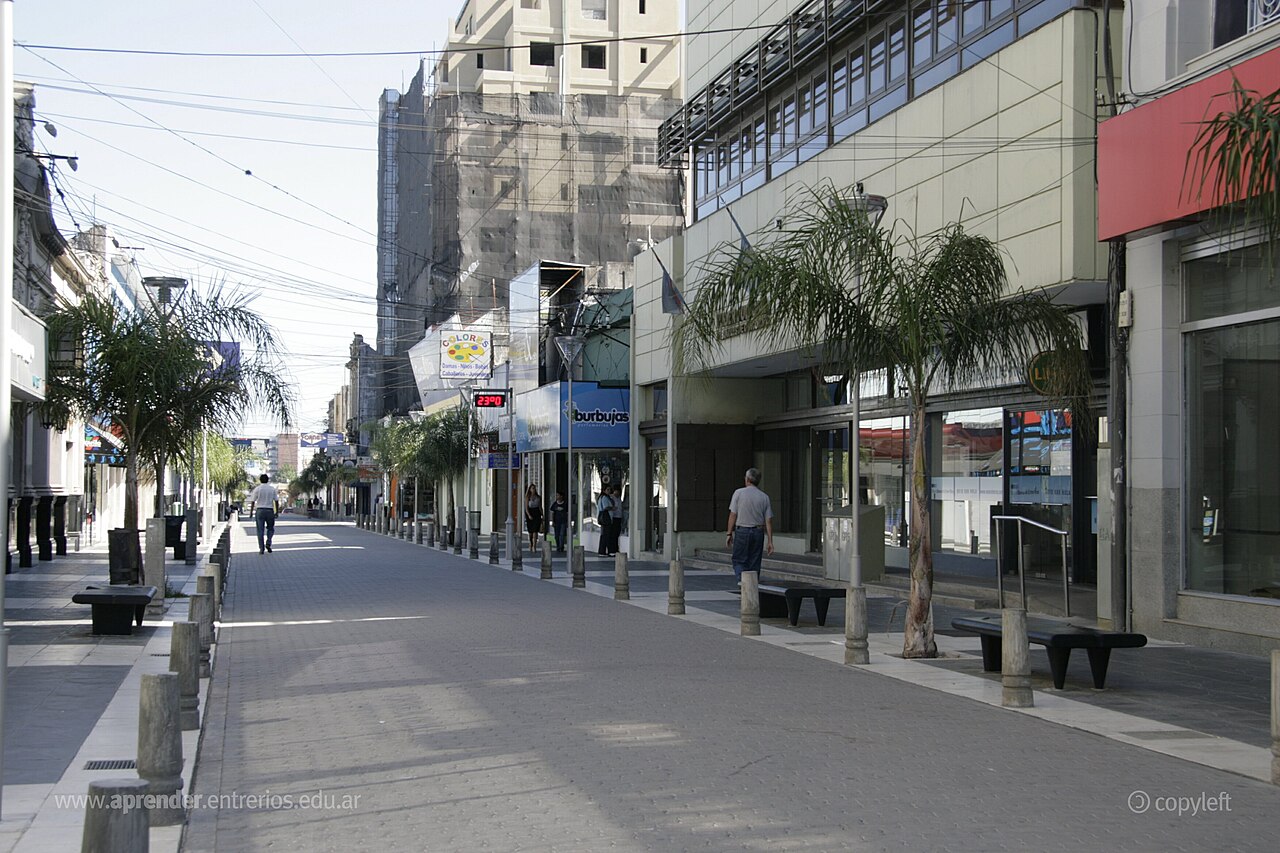 Calle peatonal céntrica de la ciudad de Concordia con edificios comerciales y palmeras a ambos lados.