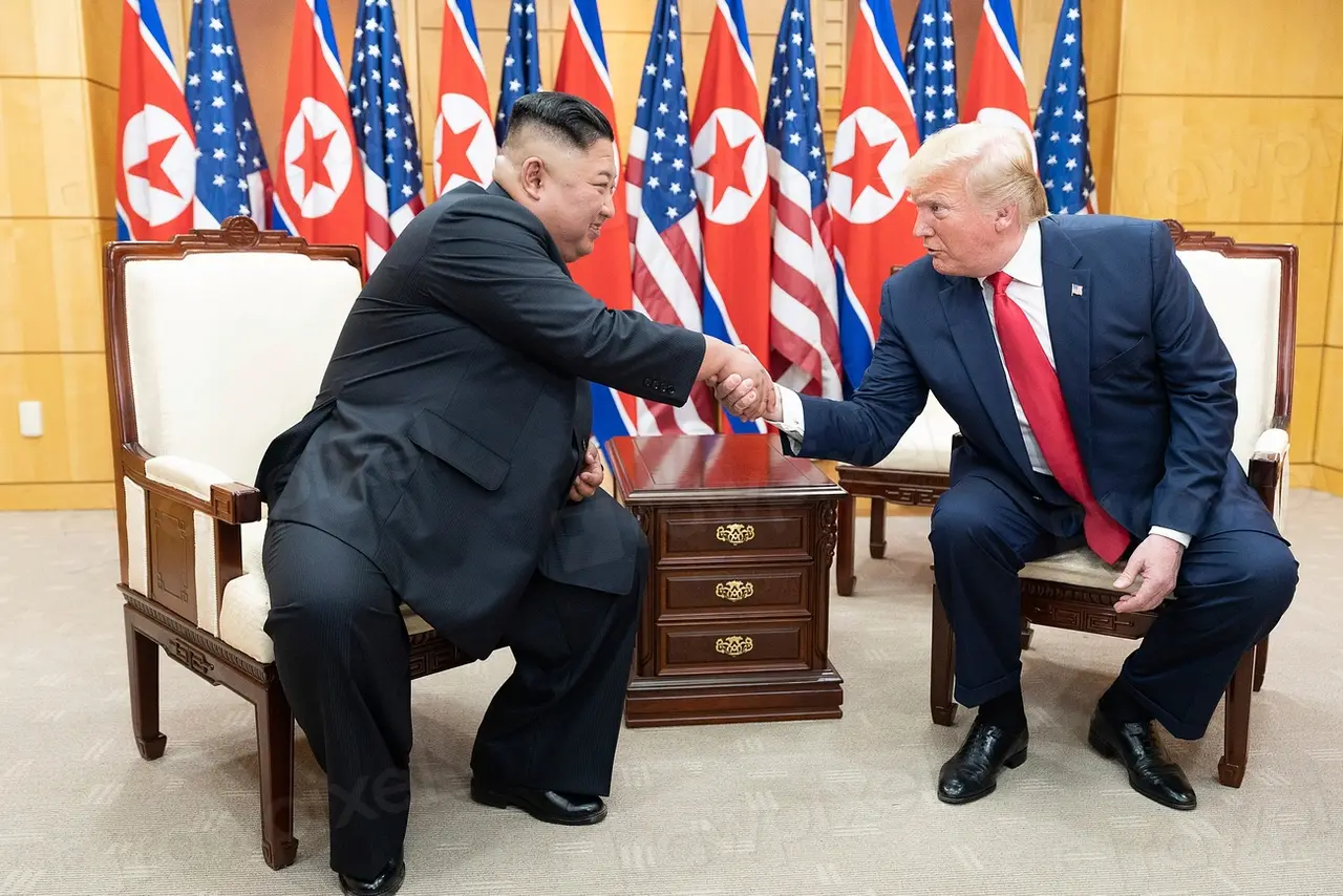 唐纳德·特朗普与金正恩在两国国旗前握手。