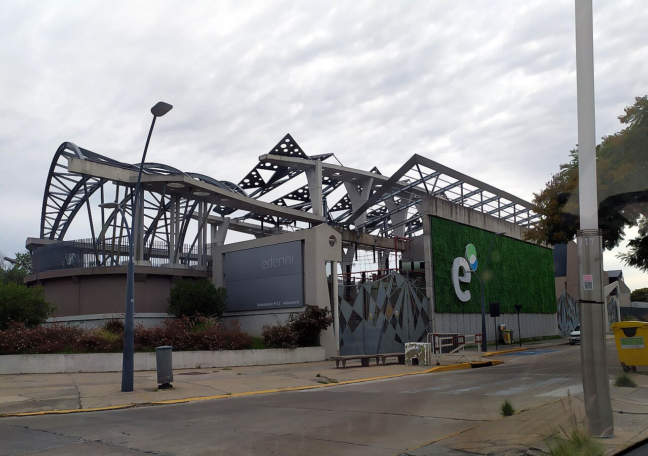 Vista exterior de una subestación eléctrica de la empresa Edenor con estructura metálica y vegetación.