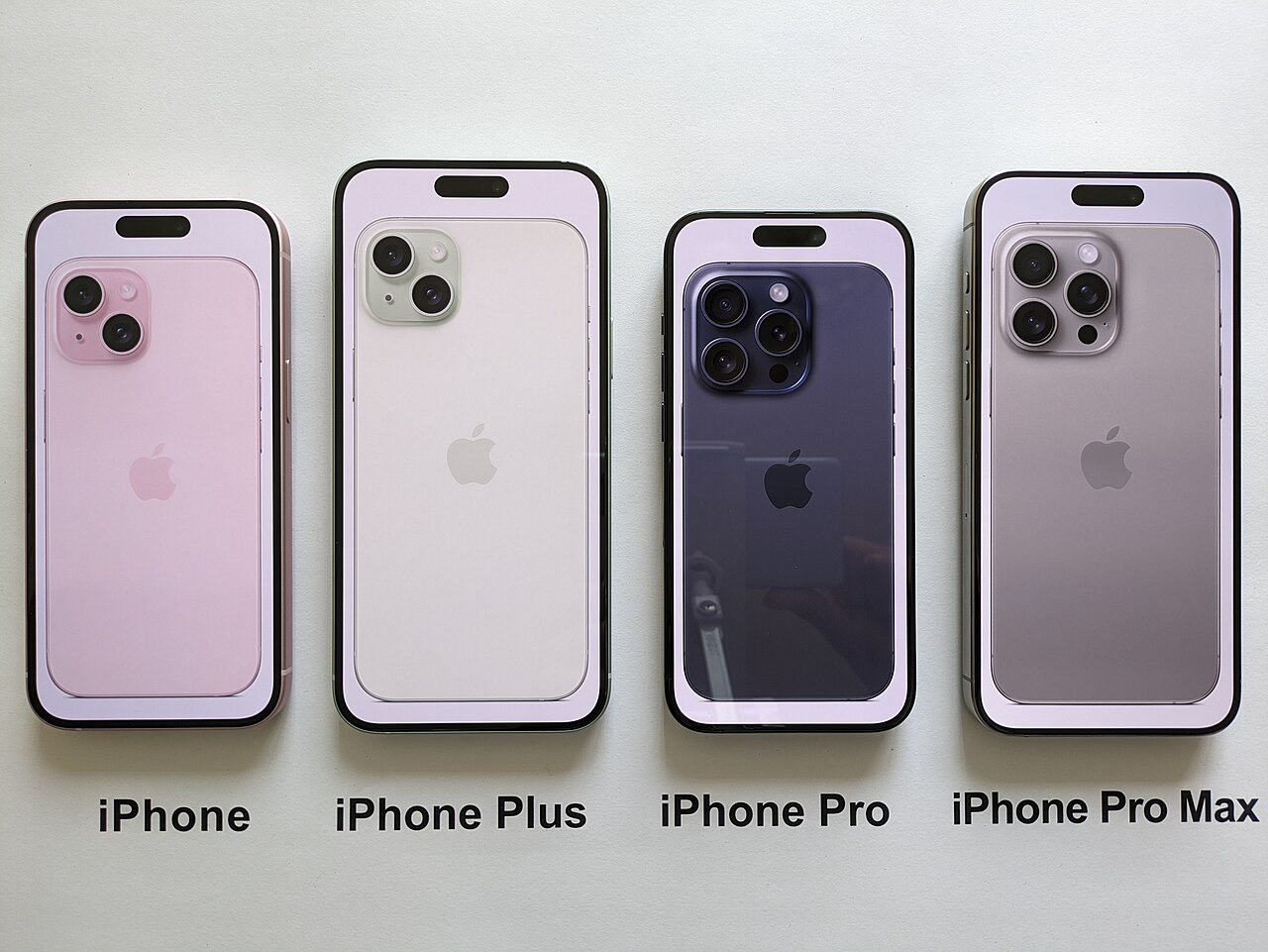 Cuatro modelos diferentes de iPhone alineados sobre una superficie blanca clara.