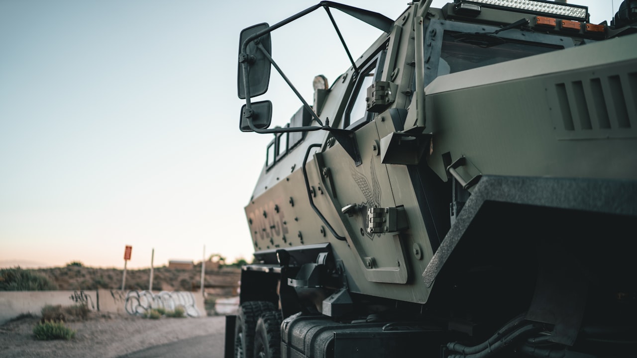 Un camión militar de gran porte se encuentra estacionado al costado de un camino rural.