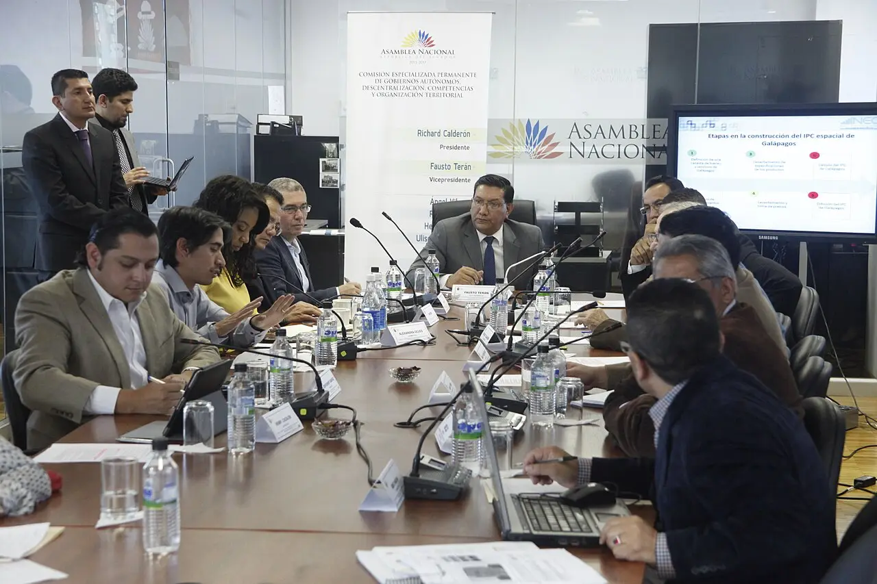 Funcionarios reunidos en una mesa de trabajo analizando datos estadísticos en una pantalla grande.