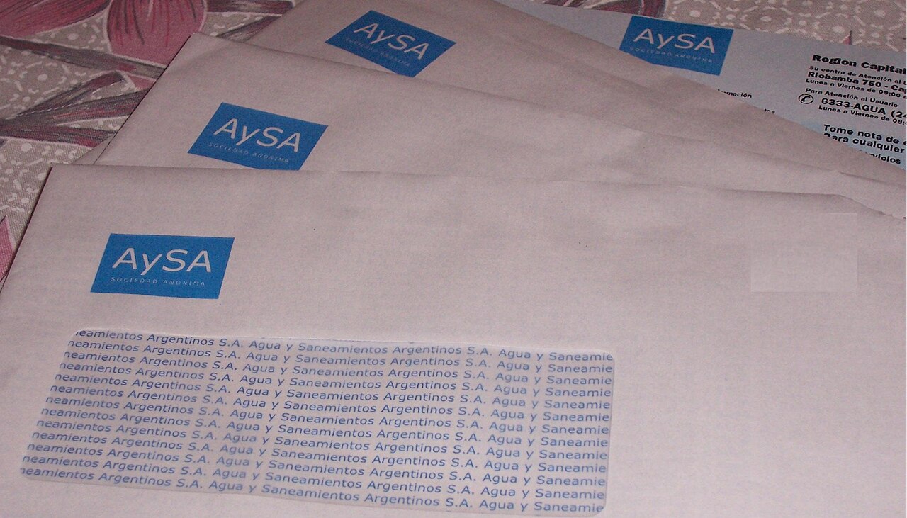 Varios sobres de correspondencia con el logotipo de la empresa AySA apilados sobre una mesa.