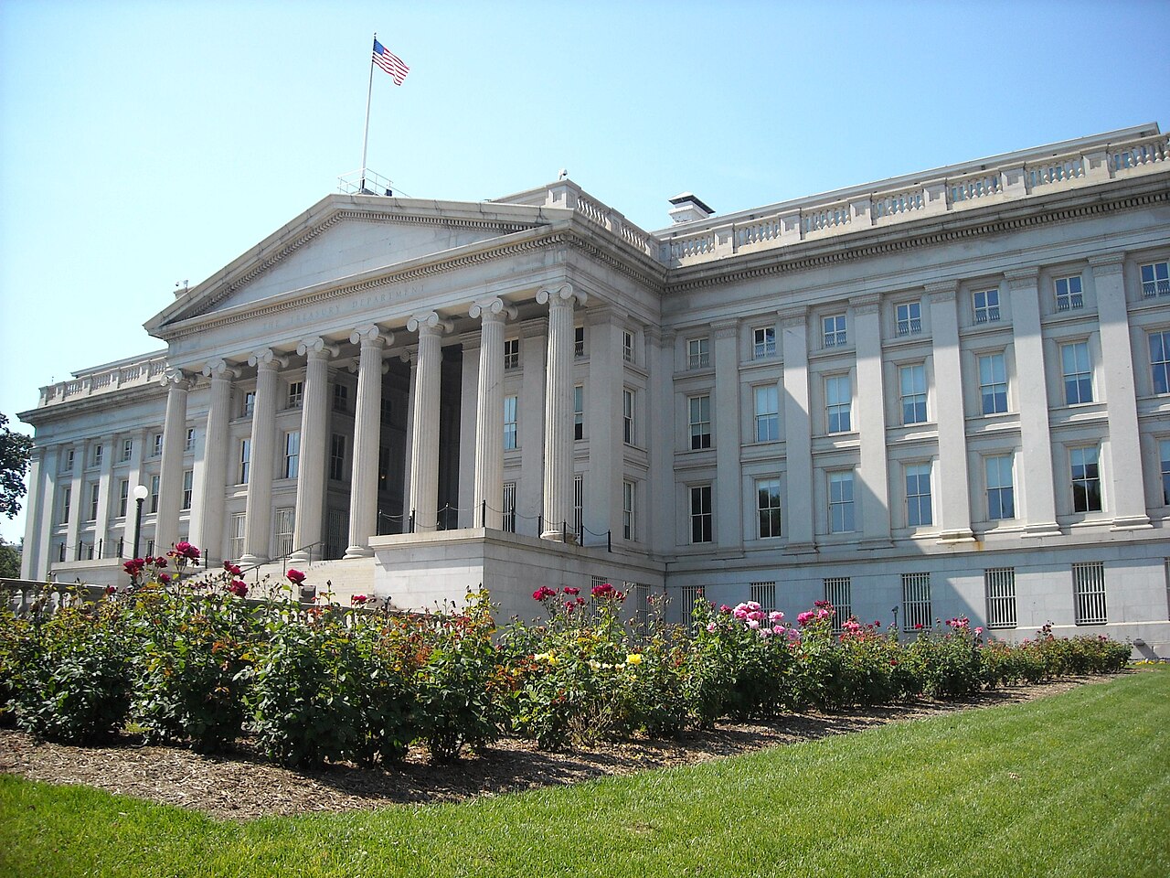 Fachada del edificio del Departamento del Tesoro de los Estados Unidos con jardines al frente.