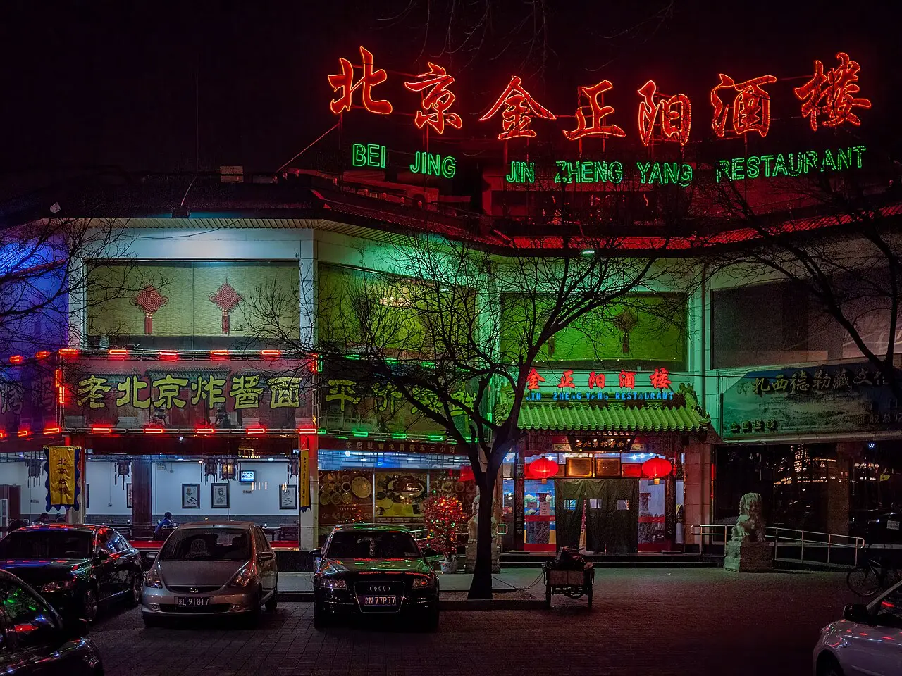 Fachada iluminada de un restaurante tradicional en Beijing durante la noche con carteles luminosos.