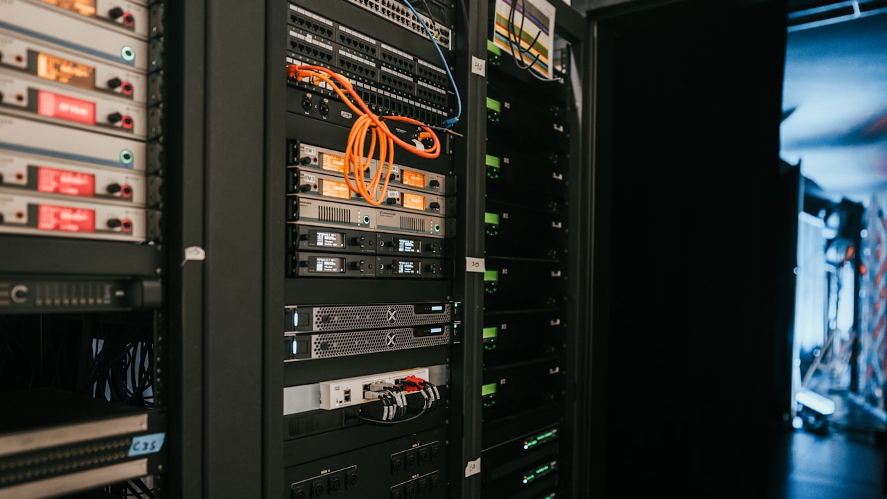 Primer plano de un rack con servidores y cables en una sala de tecnología iluminada.