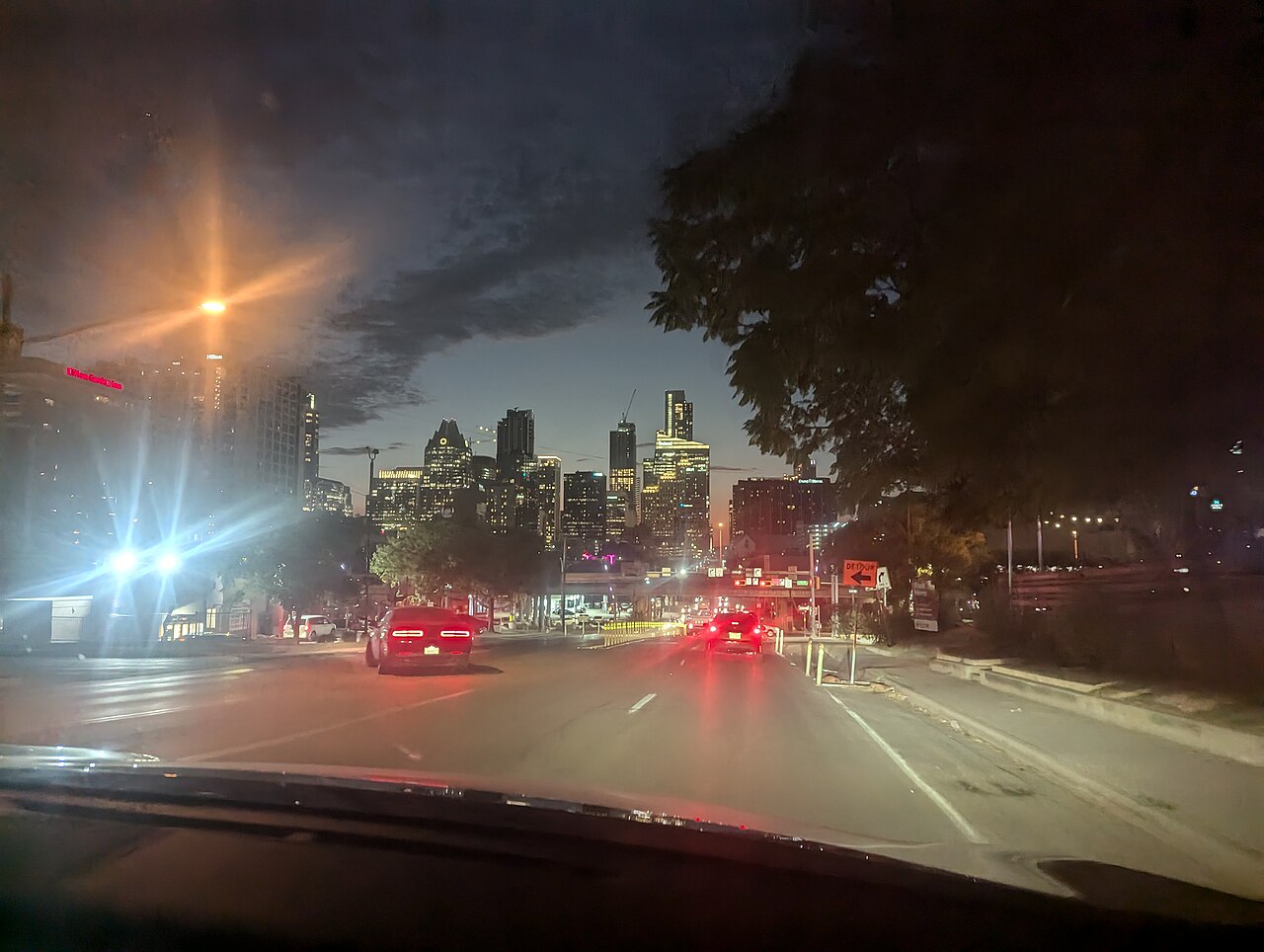 Vista nocturna desde un vehículo hacia el horizonte iluminado de la ciudad de Austin.