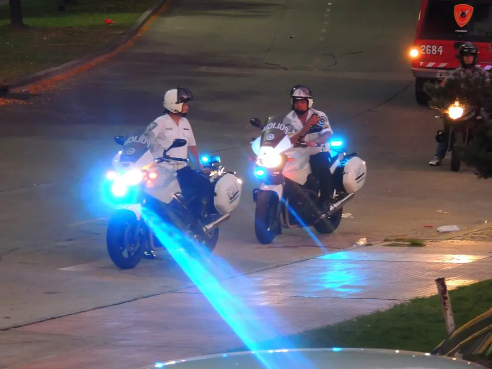 Dos efectivos de la Policía Federal Argentina patrullan en motocicletas con las luces encendidas.