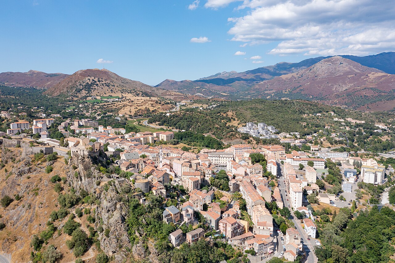 Vista aérea panorámica de la ciudad con montañas de fondo bajo un cielo despejado.