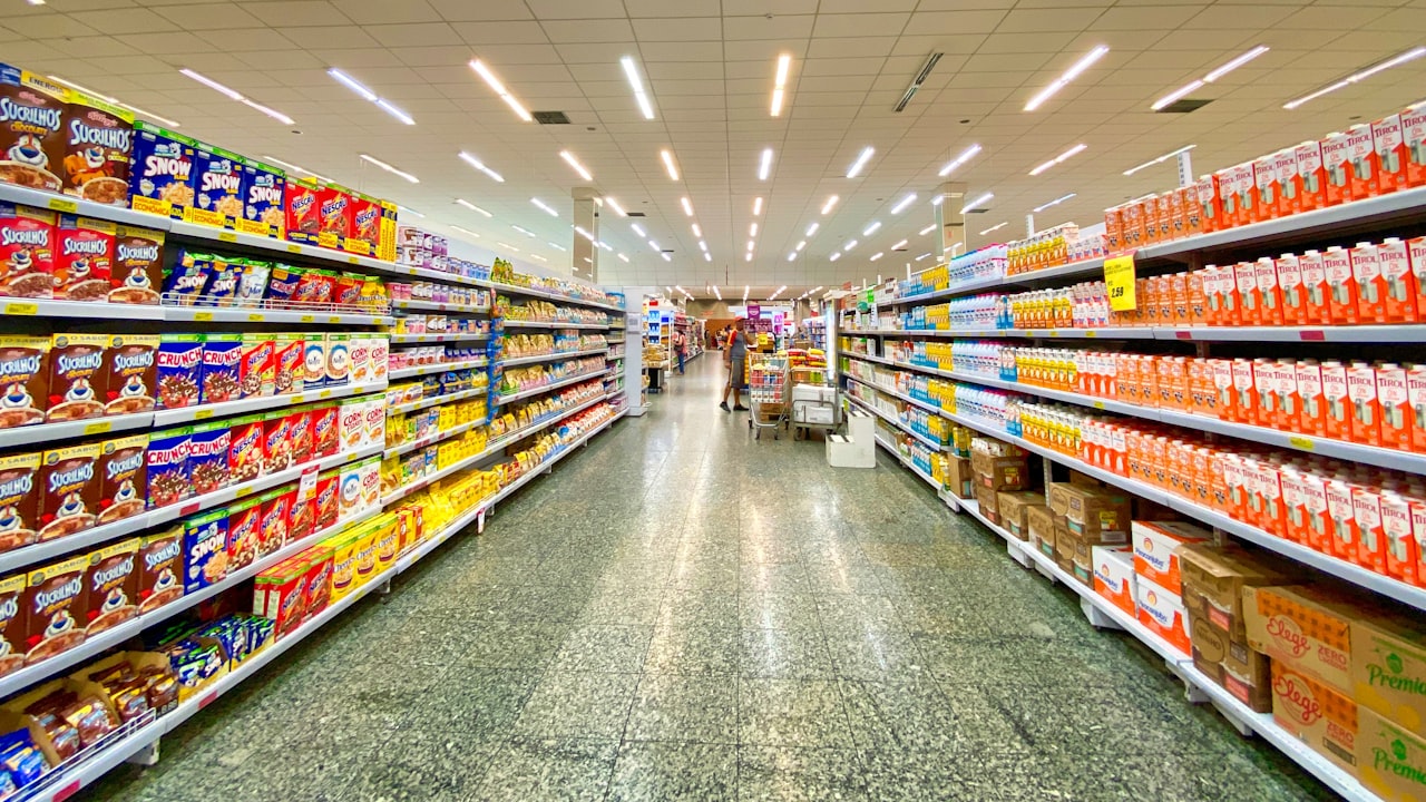 Pasillo de un supermercado con estanterías llenas de productos alimenticios y bebidas a la venta.