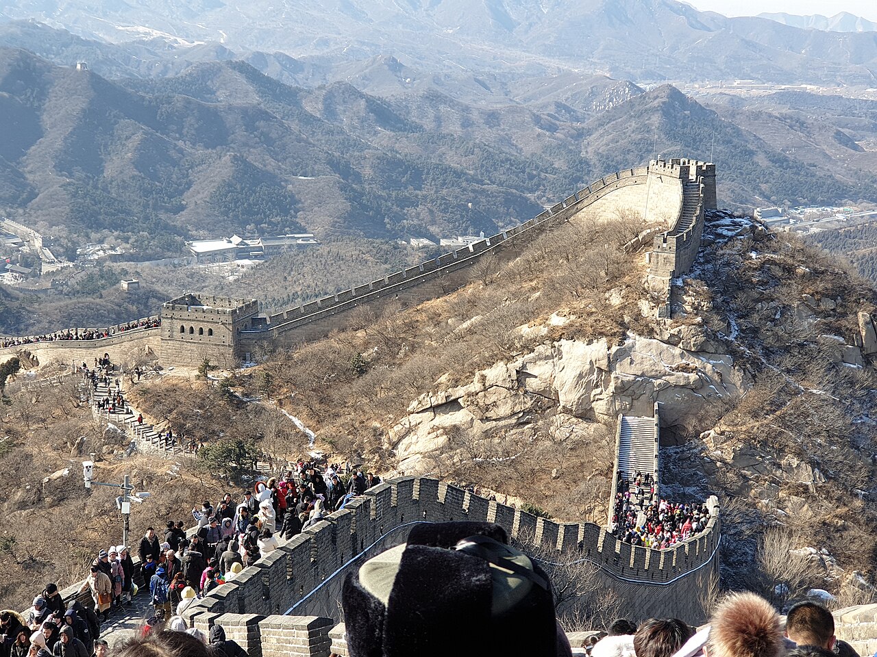 游客们在万里长城上行走,背景是连绵起伏的山脉。