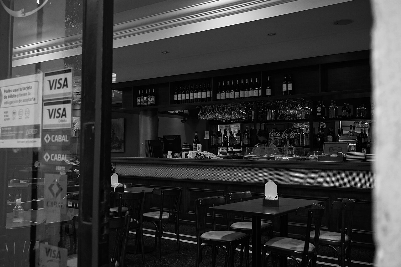 Interior de un bar tradicional en el microcentro porteño con mesas y barra de madera.
