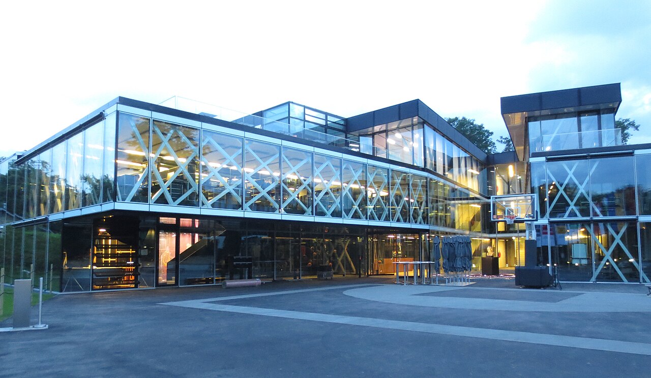 Edificio moderno de cristal con un aro de básquet en su fachada exterior.