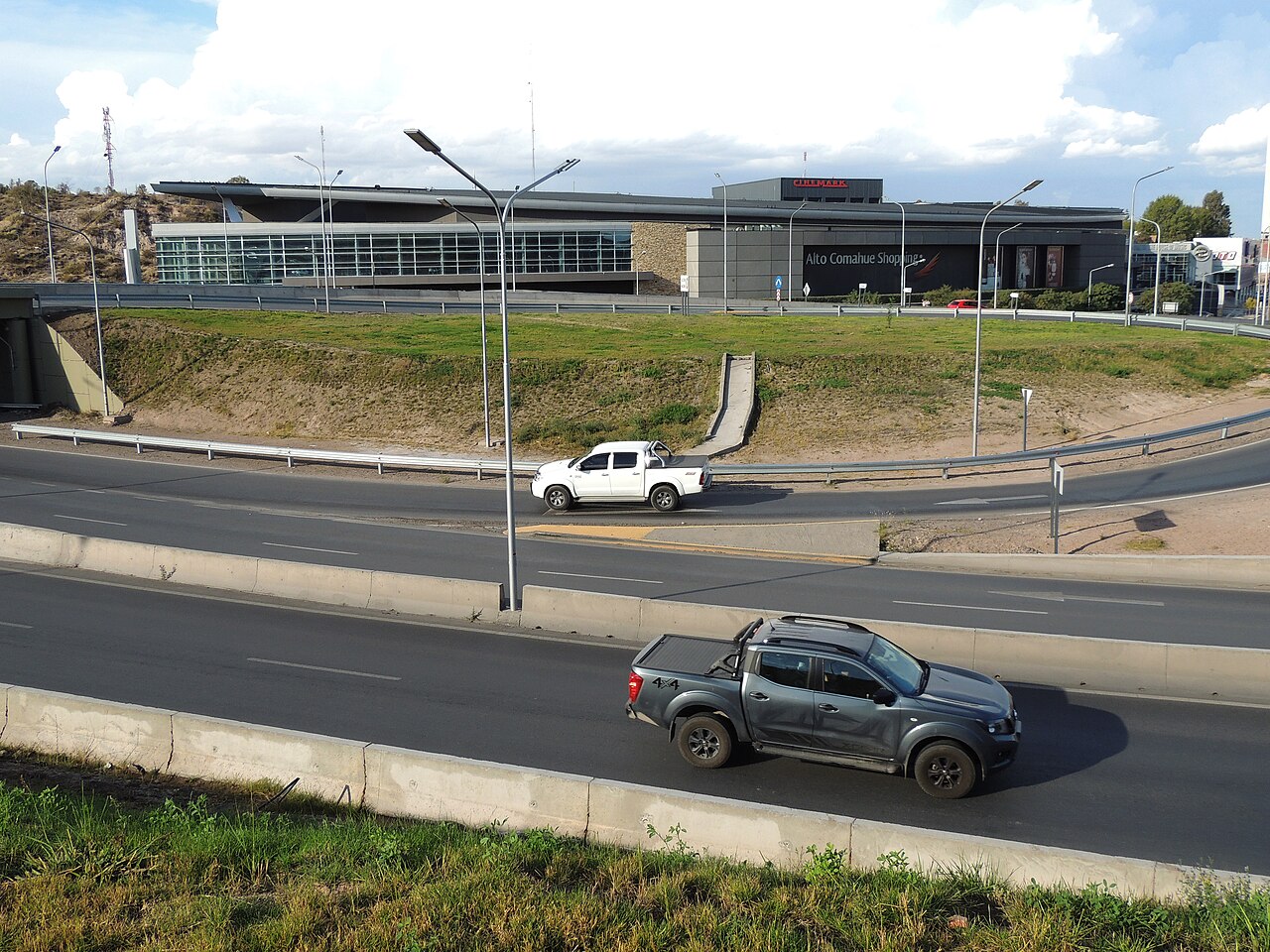 Vehículos circulando por una autopista frente a un edificio comercial en Neuquén.