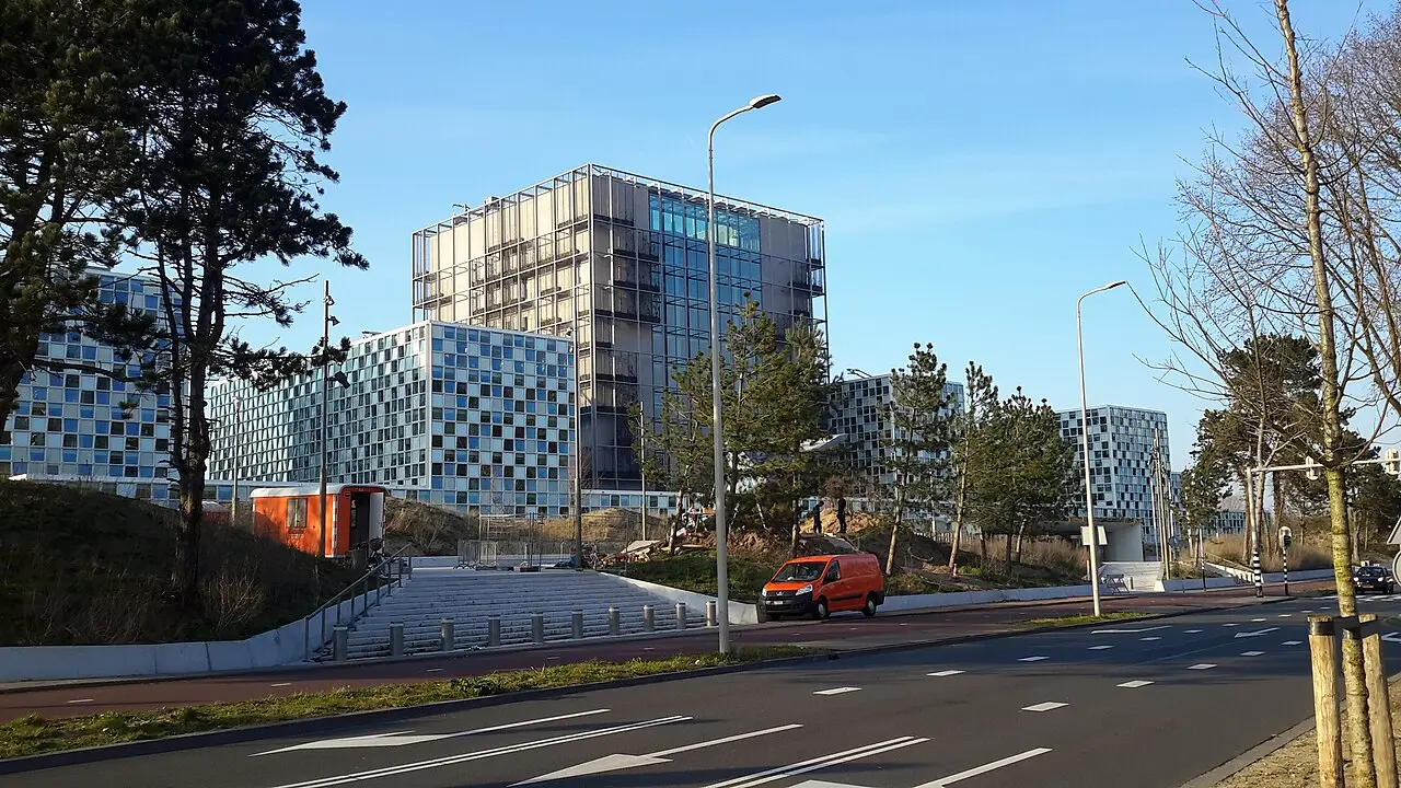 国际刑事法院大楼外观，前景有树木和街道。