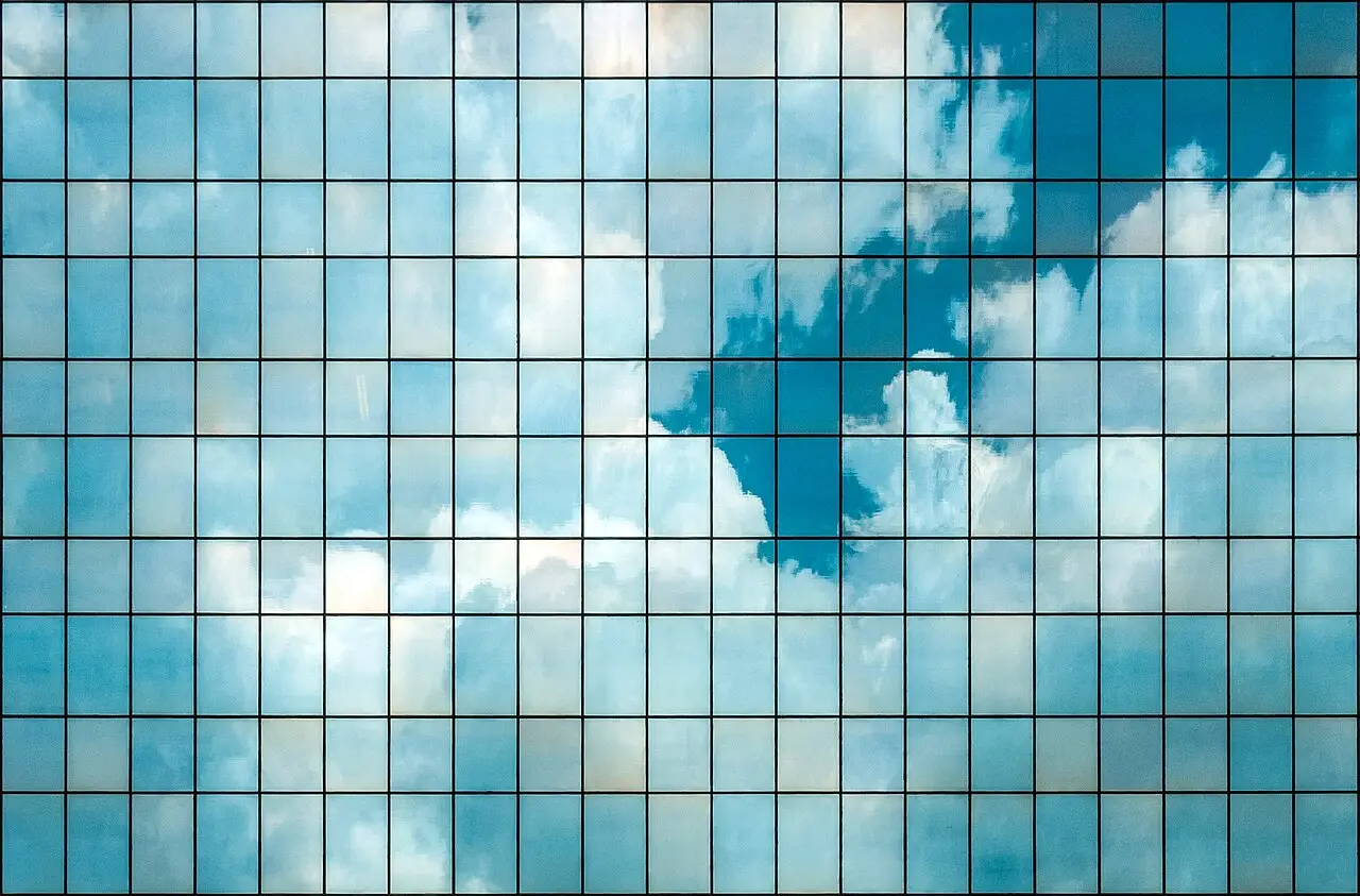 Fachada de vidrio de un edificio moderno en Brasil que refleja el cielo nublado.