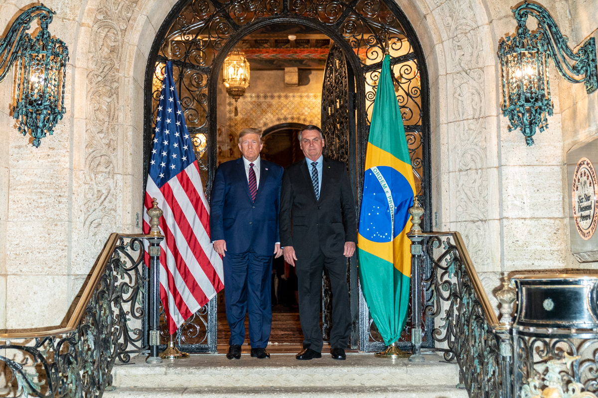Donald Trump y Jair Bolsonaro posan juntos frente a banderas de Estados Unidos y Brasil.