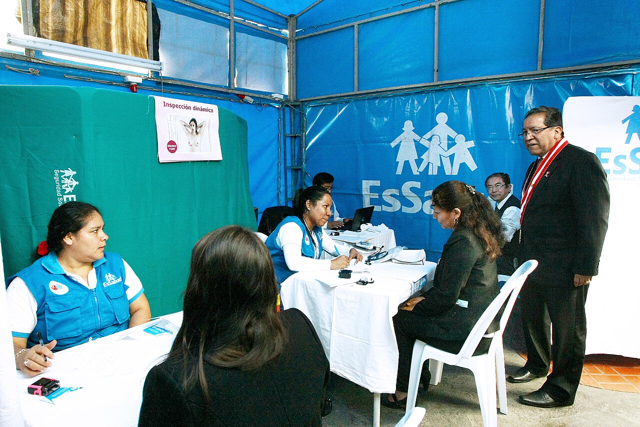 Personal de salud atendiendo a una paciente en un puesto médico improvisado con carpas azules.