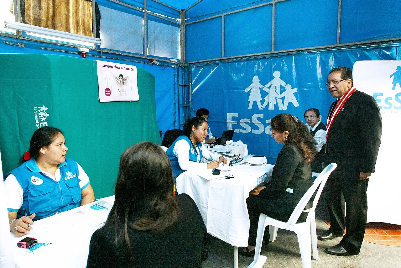 Personal de salud atendiendo a una paciente en un puesto médico improvisado con carpas azules.