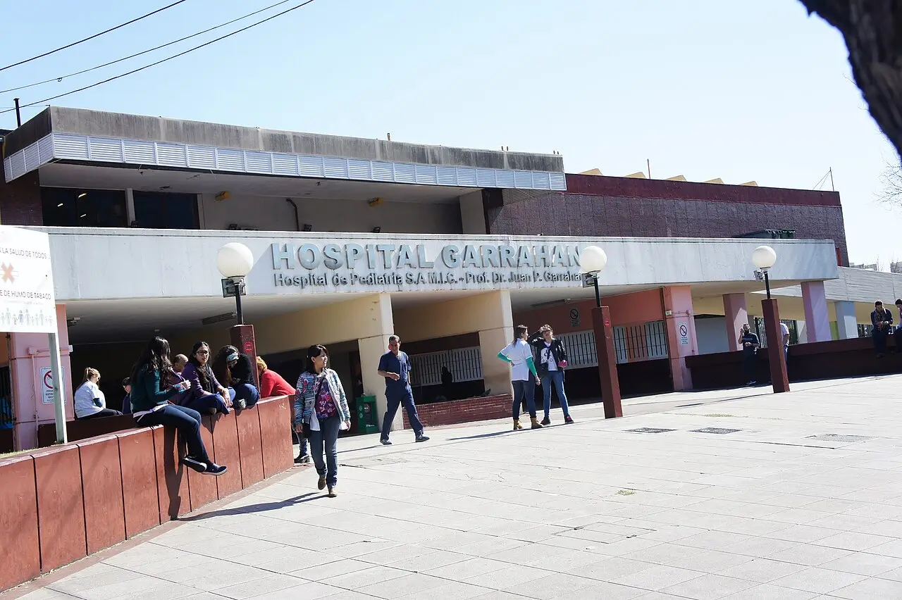 Fachada del Hospital Garrahan con personas caminando en la entrada durante un día soleado.