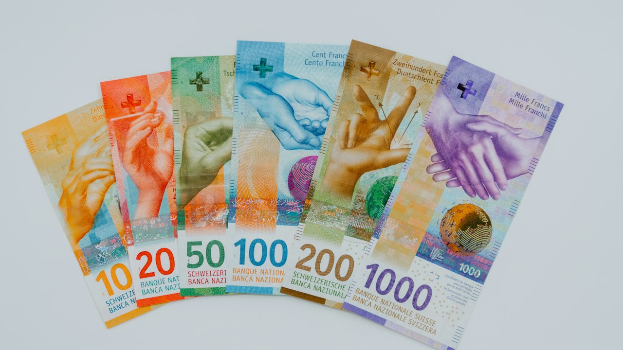 Varios billetes de distintas denominaciones dispuestos en abanico sobre una superficie blanca.