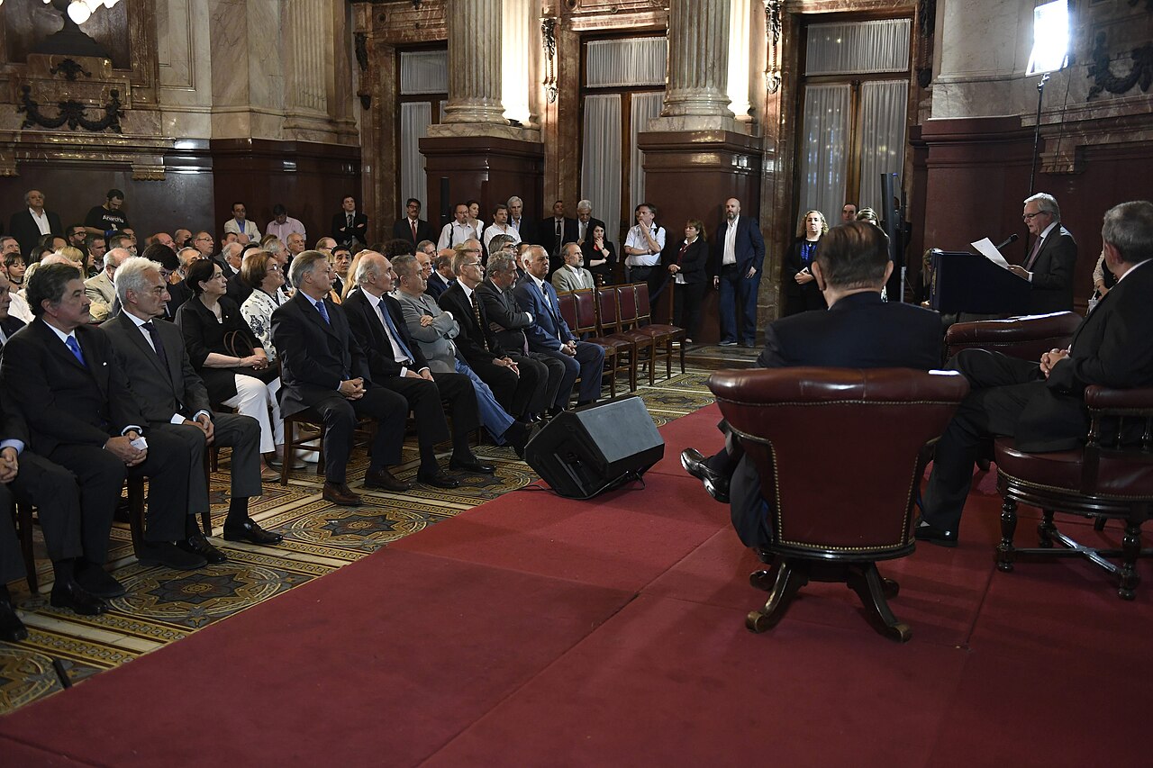Personas sentadas en un salón formal durante un evento oficial en el Senado.