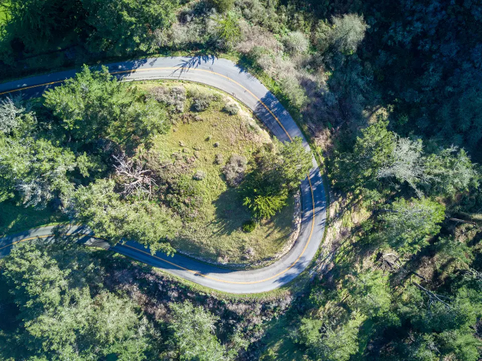 Vista aérea de una carretera asfaltada que serpentea a través de un bosque denso y verde.