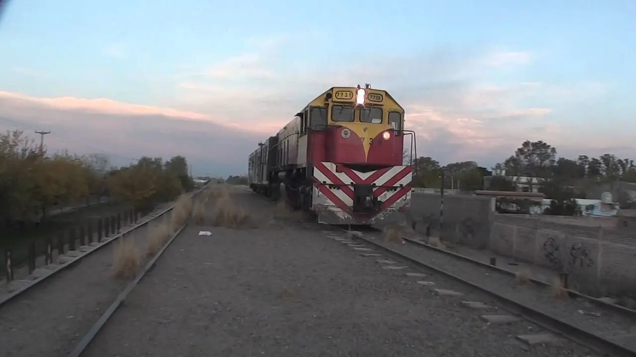 Una locomotora de tren con esquema de colores rojo y amarillo avanza por las vías.