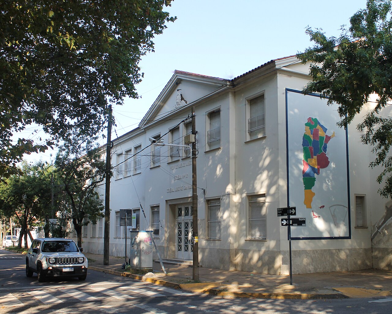 一所古老学校建筑的外观,外墙上挂着一张阿根廷地图。