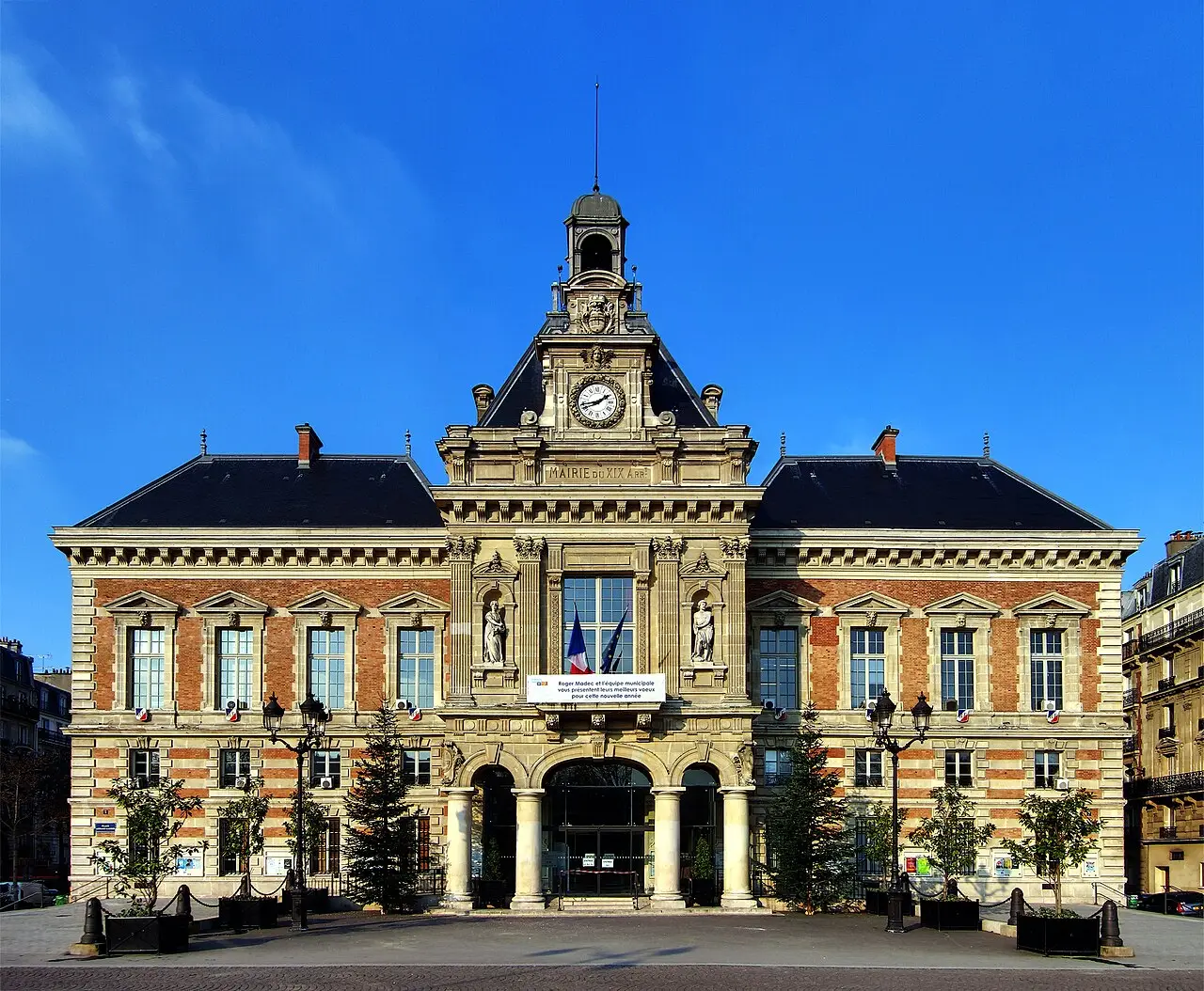 Imponente edificio municipal histórico de arquitectura clásica francesa bajo un cielo azul despejado.