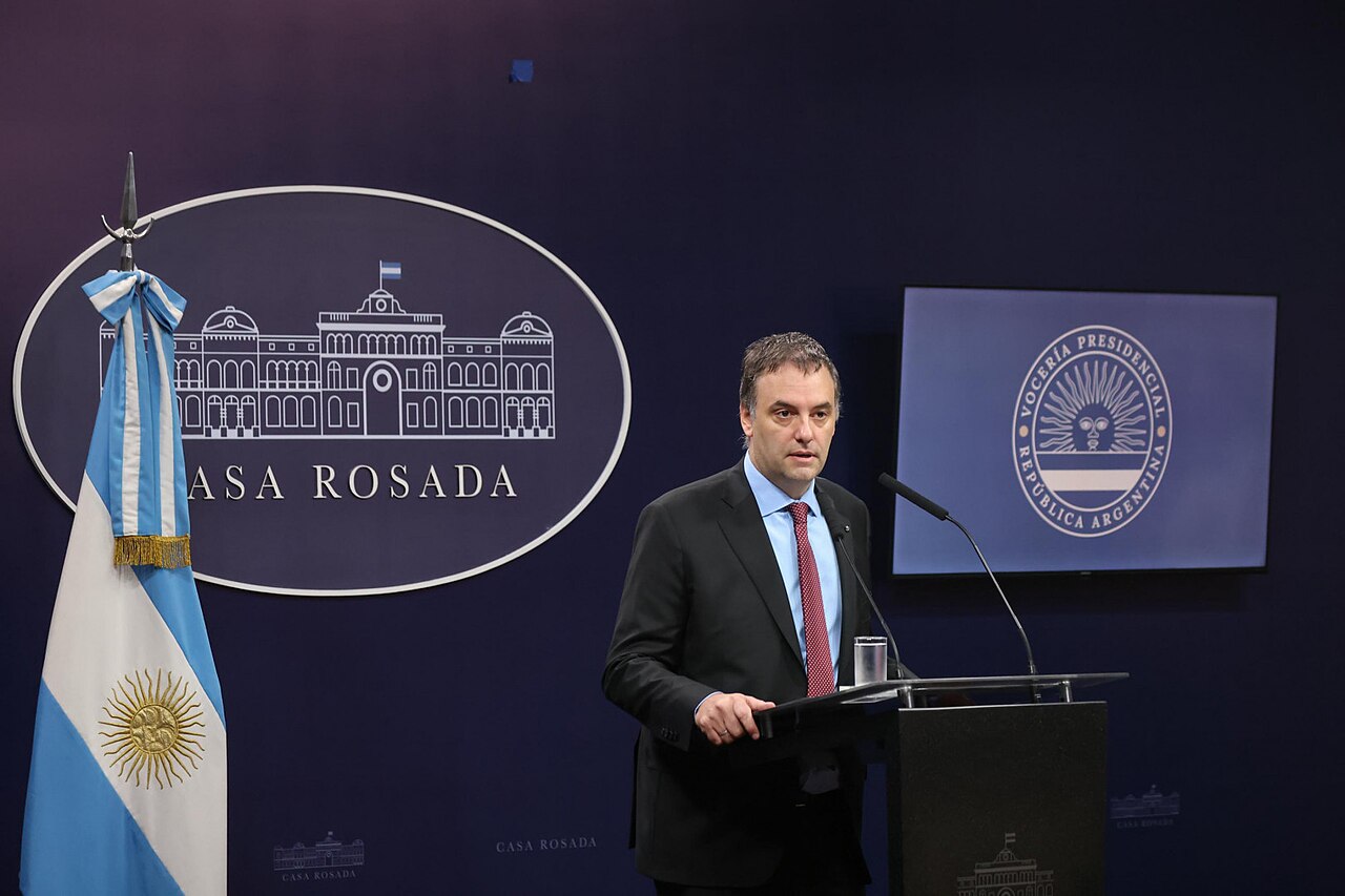 Manuel Adorni habla frente a un micrófono en una conferencia de prensa oficial.