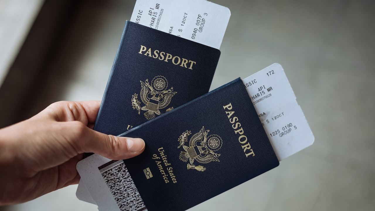Primer plano de una mano sosteniendo dos pasaportes de Estados Unidos con tarjetas de embarque.