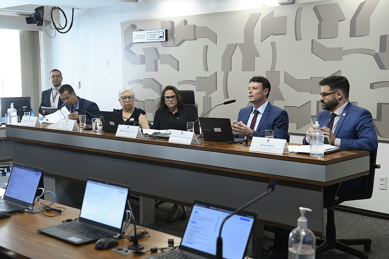 Un grupo de legisladores debate sentados en una mesa larga dentro de una sala legislativa.