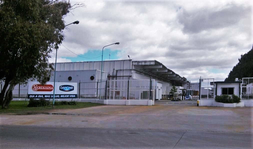 Fachada de la planta industrial de la empresa láctea con cartelería de marcas reconocidas.