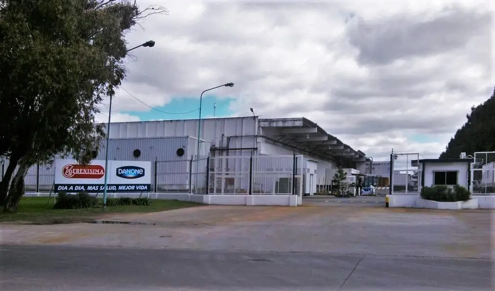 Fachada de la planta industrial de la empresa láctea con cartelería de marcas reconocidas.