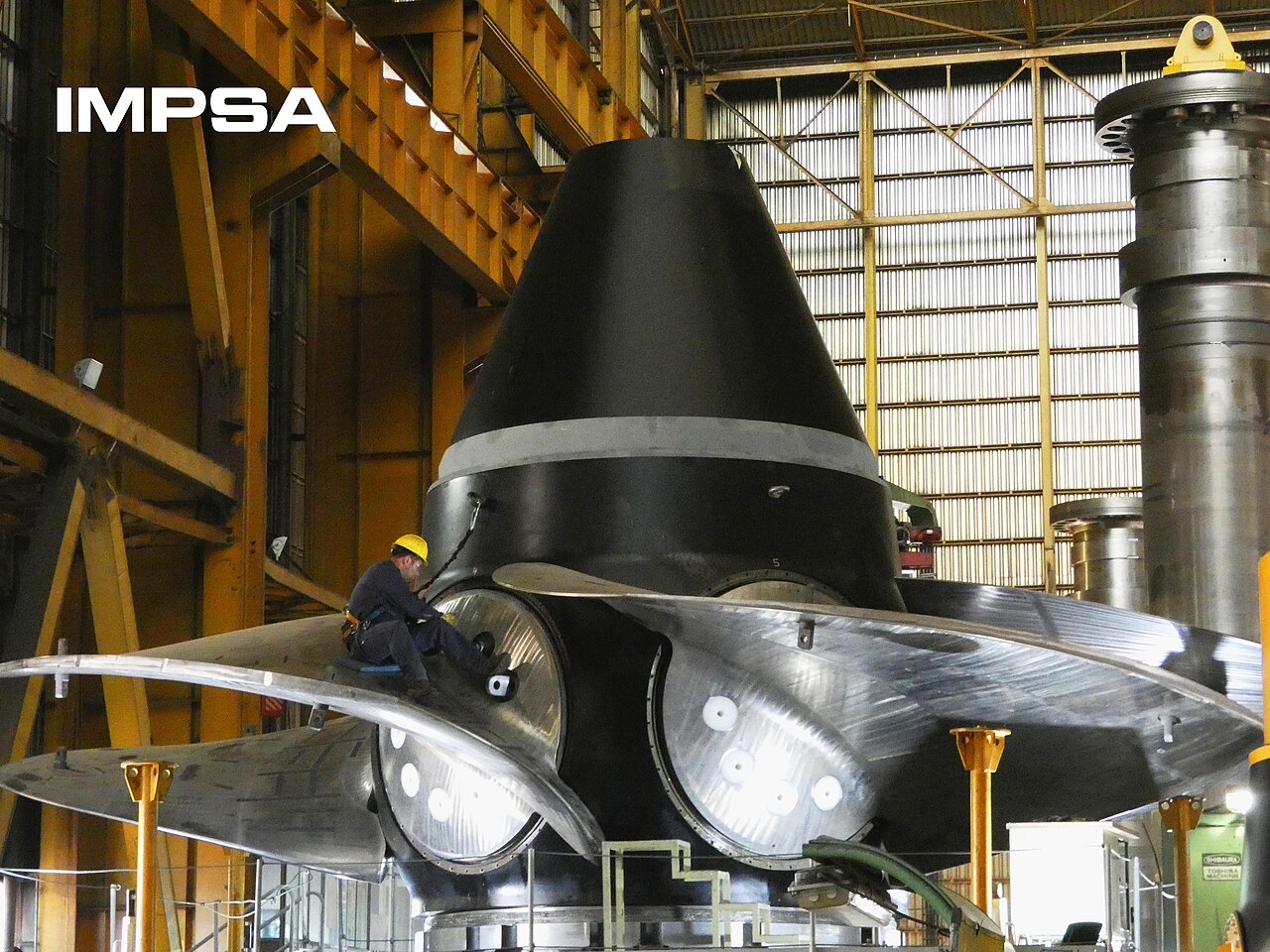Un operario con casco trabaja sobre el rodete metálico de una turbina industrial.