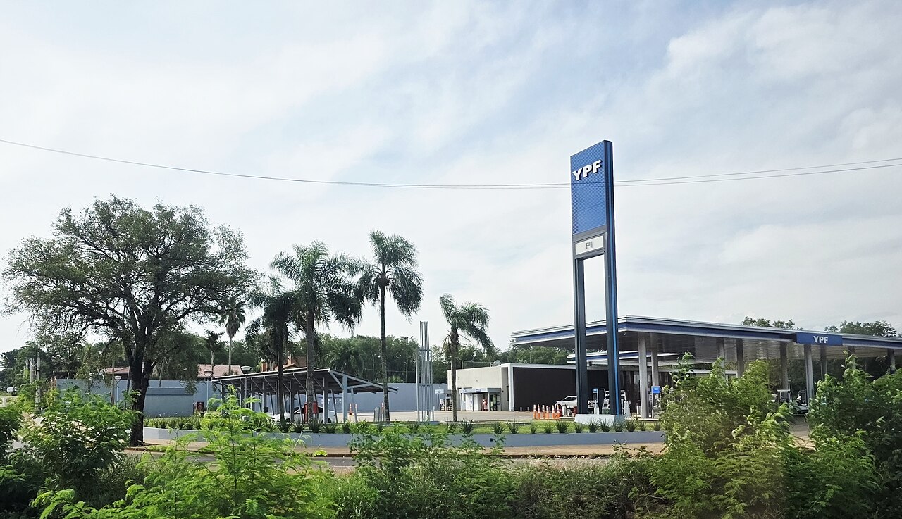 Estación de servicio YPF con su característico cartel azul sobre una ruta rodeada de vegetación.